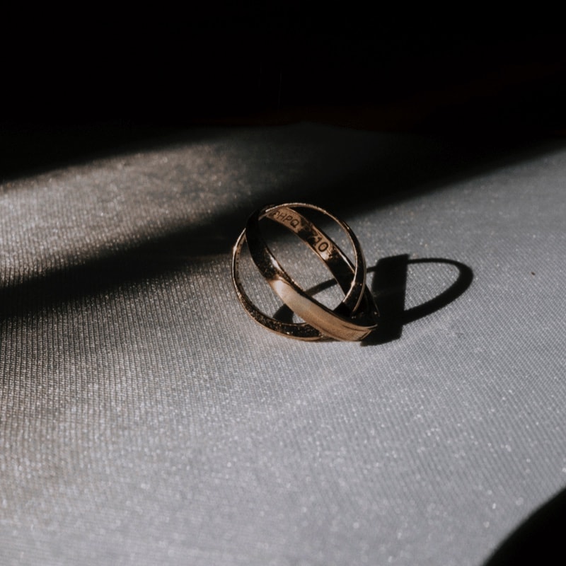 Two crossed gold rings lays on the
                                    gray colour fabric